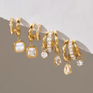 Gros plan de boucles d'oreilles en C en acier doré avec des breloques en zircon cubique