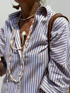 Detailed view of a striped lapel shirt dress styled with layered seashell jewelry