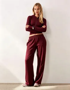 Vista di una donna che indossa un set di felpa con cappuccio bordeaux e pantaloni larghi.