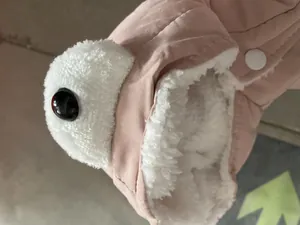 Close-up detail of pink pet winter coat with soft white fleece lining and eye decoration