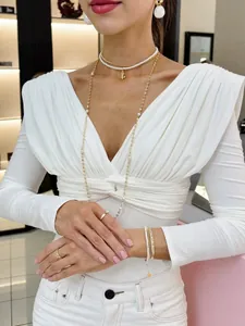 Elegante top blanco de manga larga con cuello en V drapeado y diseño entallado