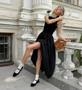 Elegant Hepburn-style sleeveless black midi dress in a vintage architectural setting