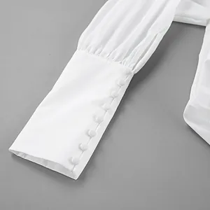 Nahaufnahme einer eleganten weißen Bluse mit langen Ärmeln und Zierknöpfen an der Manschette