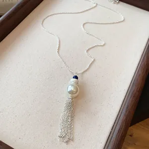 Dettaglio di un'elegante collana con perla e nappa su un vassoio di stoffa