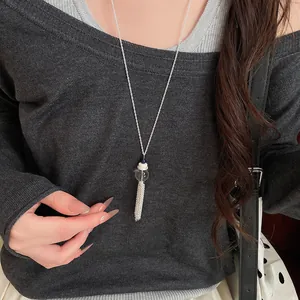 Vista dettagliata di un'elegante collana con nappa in vetro indossata su un maglione