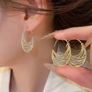Dettaglio di orecchini pendenti ovali vintage dorati e traforati indossati dal modello