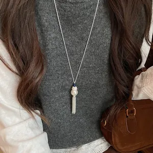 Dettaglio di una collana con nappa in stile coreano con accenti di perle e vetro blu.