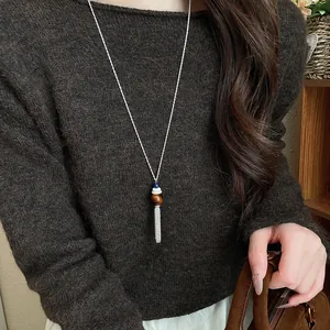 Dettaglio di una collana con nappine stile coreano su un maglione marrone