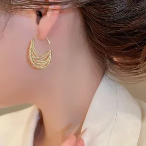 Primo piano di un elegante orecchino a cerchio ovale vintage dorato su modella asiatica