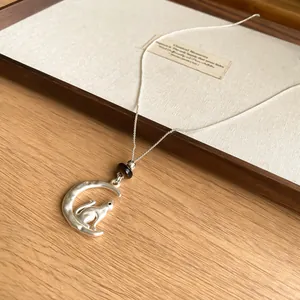 Elegant silver-tone cat sitting on a crescent moon pendant necklace with brown bead detail