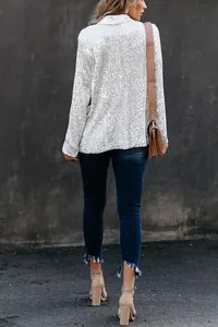 Rear view of a dazzling silver sequined blazer jacket paired with blue skinny jeans