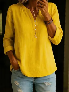 Detail of yellow cotton linen blouse featuring a V-neckline and decorative white buttons.