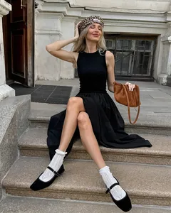Elegant sleeveless Hepburn style black knit dress shown in a lifestyle street setting
