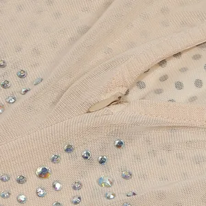 Primo piano di un body in rete beige con strass scintillanti e chiusura a zip invisibile.