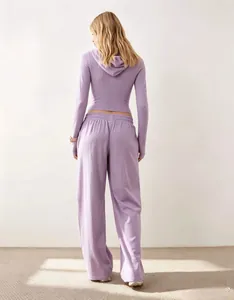 Vista posteriore di una felpa corta con cappuccio viola e pantaloni a gamba larga.