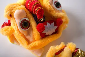 Detailed close-up of a plush yellow lion dance dog costume with sequins and gold bells