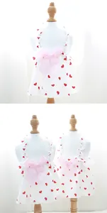 Close-up detail of a white pet summer dress with red heart prints and a large pink bow.