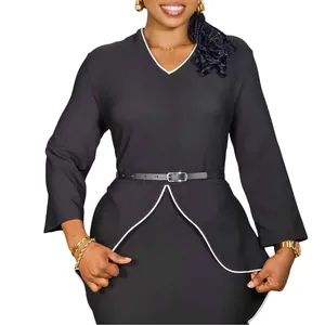 Close-up detail of black professional peplum dress featuring white trim and waist belt