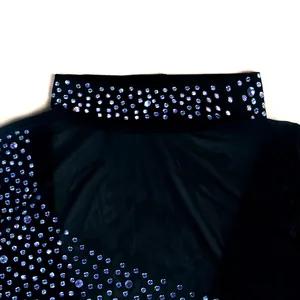 Detalle de pedrería plateada brillante en la zona del cuello de malla negra.