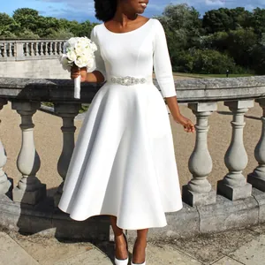 Elegantes weißes Midi-Abendkleid mit Strassgürtel und 3/4 Ärmeln in Gartenumgebung.