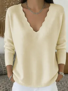 Close-up of a cream knit sweater featuring a unique scalloped V-neckline design.