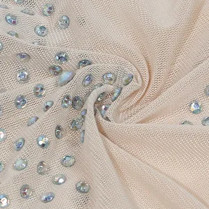 Dettaglio macro del tessuto a rete beige con strass iridescenti e scintillanti