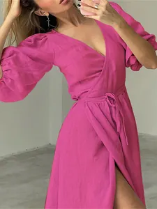 Close-up detail view of elegant fuchsia wrap dress with puff sleeves and adjustable waist tie