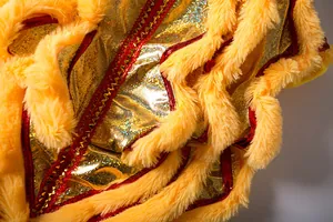 Macro detail of pet lion dance costume showing plush yellow faux fur and gold sequins