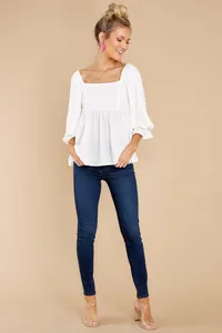 Model wearing a minimalist white square neck blouse with elegant puff sleeve details