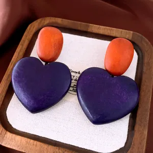 Close-up detail of vintage wooden heart-shaped earrings with purple and orange finish