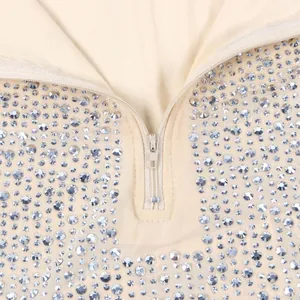 Dettaglio di vestito in rete beige con strass scintillanti e cerniera frontale dorata