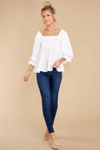 Detail view of a white square-neck puff-sleeve blouse with ruffled cuffs