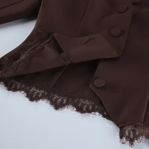 Gedetailleerde close-up van bruine blazer met delicaat kant en beklede knopen.