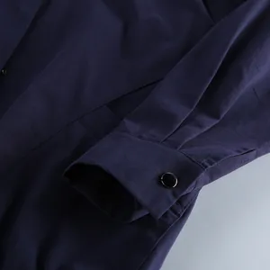 Gedetailleerde weergave van de mouw van een donkerblauwe katoenen jas met zwarte knoop