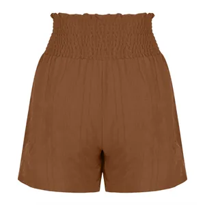 Detail view of high-waisted brown shorts with smocked elastic waistband and textured fabric.