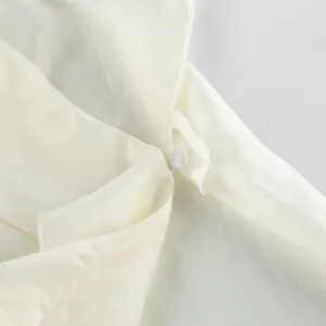Close-up detail showing the fabric-covered button and loop on an off-white Tencel wrap top