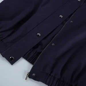Detailopname van een marineblauw katoenen jack met een metalen rits en zilveren drukknopen