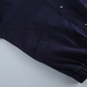 Detailopname van een marineblauwe katoenen werkjas met metalen drukknopen en zak