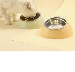 Gros plan d'un chat blanc mangeant dans un bol incliné en acier inoxydable pour son cou