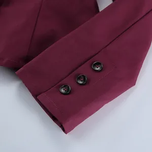 Dettaglio ravvicinato di tre bottoni sul polsino del blazer bordeaux con trama del tessuto
