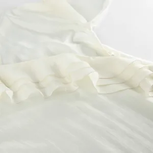 Close-up detail of white ruffled tencel fabric showing soft texture and sheen