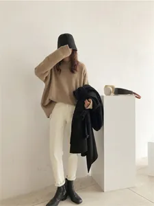 Femme portant un pull en maille rétro kaki avec un pantalon blanc et des bottes noires