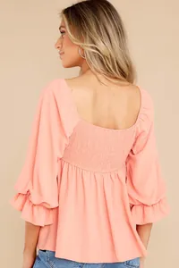 Back view of coral pink square neck blouse with smocked detail and ruffle sleeves