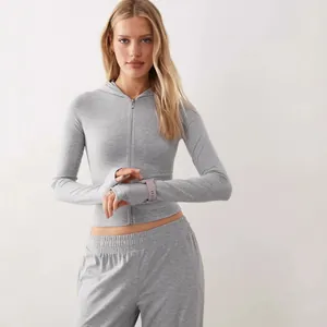 Completa tuta grigia aderente con felpa con cappuccio e zip e pantaloni coordinati.