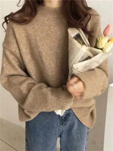 Pull en maille vintage camel à col rond pour femme, porté avec un jean bleu classique.