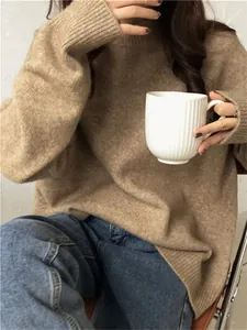 Femme portant un pull en maille marron oversize à col rond tenant une tasse blanche