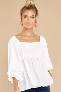 Close-up of white square-neck blouse with ruffled sleeves and lightweight fabric.