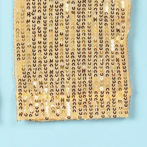Close-up of gold sequins on a mesh dress fabric showing vertical pattern detail.