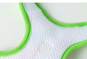 Gros plan sur le tissu en maille blanche respirante avec bordure vert fluo d'un harnais pour chien