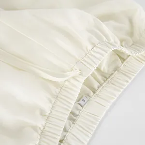 Detailed view of the elasticated waistband on cream Tencel wide-leg pants.